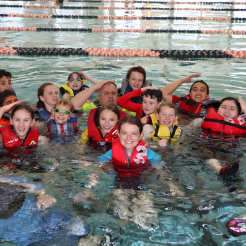 Group of students in a pool wearing life jackets
